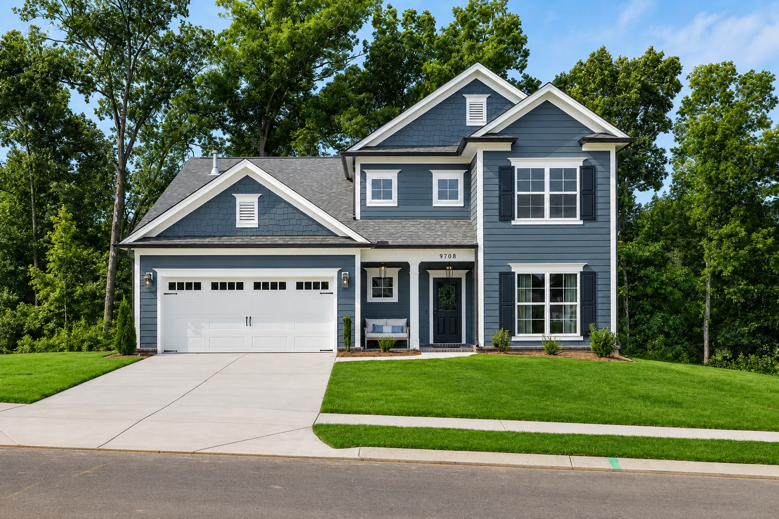 Two-story blue house with white trim, front porch, and attached garage surrounded by trees. Built by Pratt Home Builders in Chattanooga, TN.