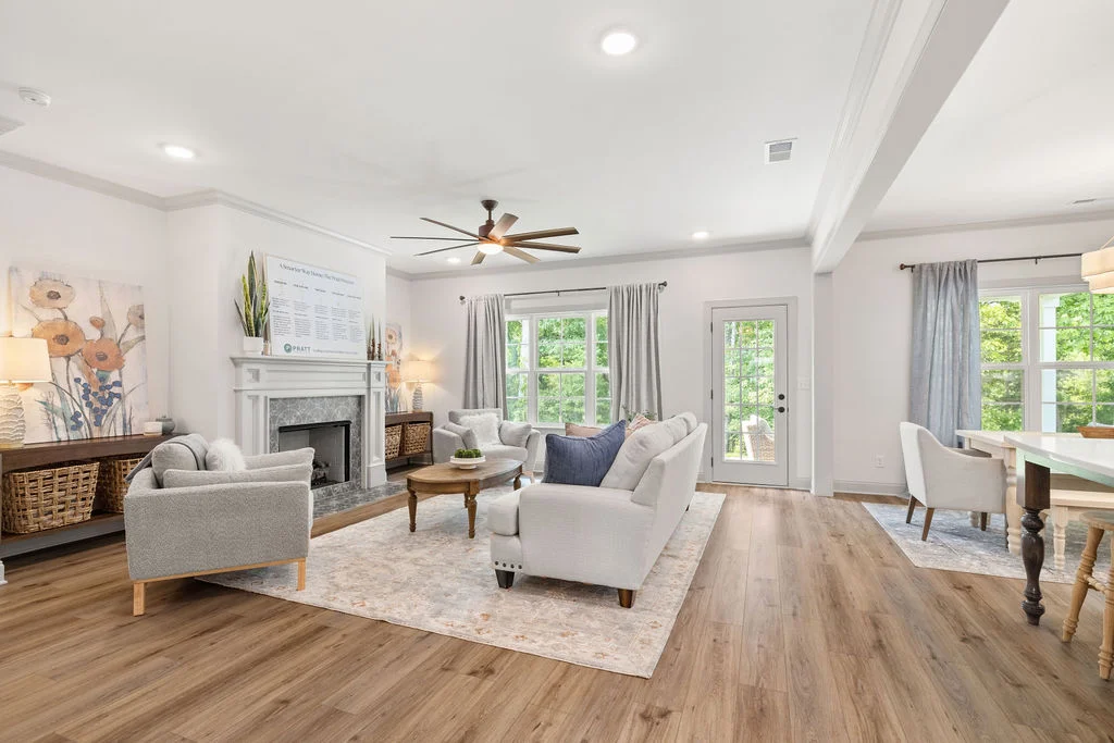 Spacious living room by Pratt Home Builders in Chattanooga TN, featuring gray sofas, wooden floors, large windows, and a decorative fireplace.