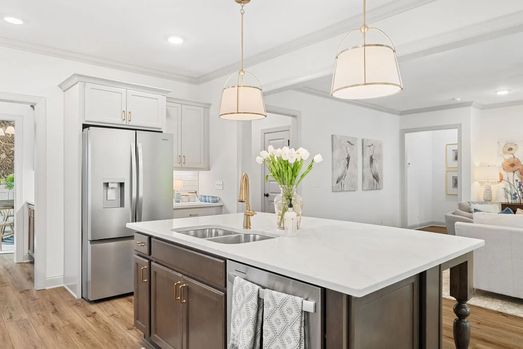 Modern kitchen by Pratt Home Builders in Chattanooga, TN, featuring marble island, stainless steel fridge, pendant lights, and vase of tulips.