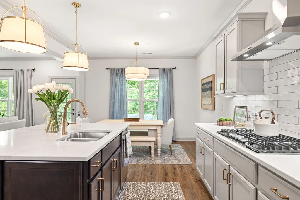 Bright kitchen and dining area with white cabinets, gas stove, island sink, and hanging lights. Designed by Pratt Home Builders in Chattanooga TN.