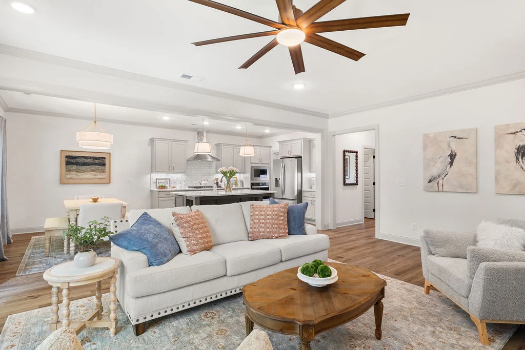 Modern living room and kitchen with cozy seating, wood floors, ceiling fan, and decor by Pratt Home Builders in Chattanooga TN.