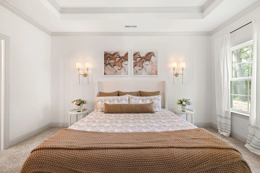 Elegant bedroom with a cozy bed, soft lighting, and floral decor by Pratt Home Builders in Chattanooga TN, highlighting a warm and inviting ambiance.