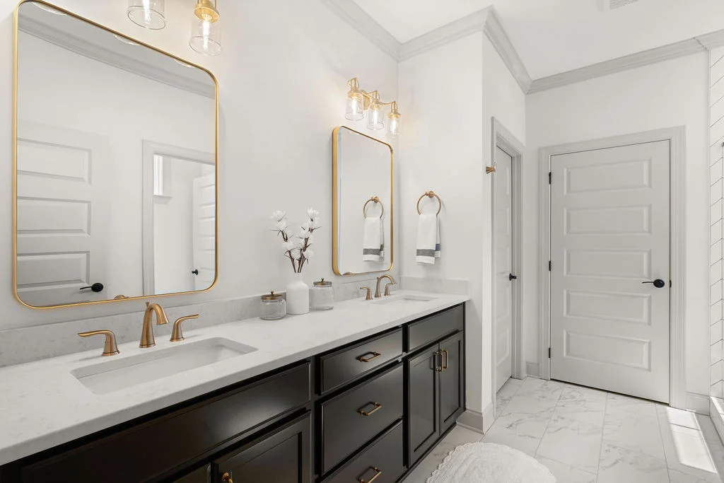 Elegant bathroom with dual sinks, gold fixtures, and large mirrors by Pratt Home Builders in Chattanooga TN.