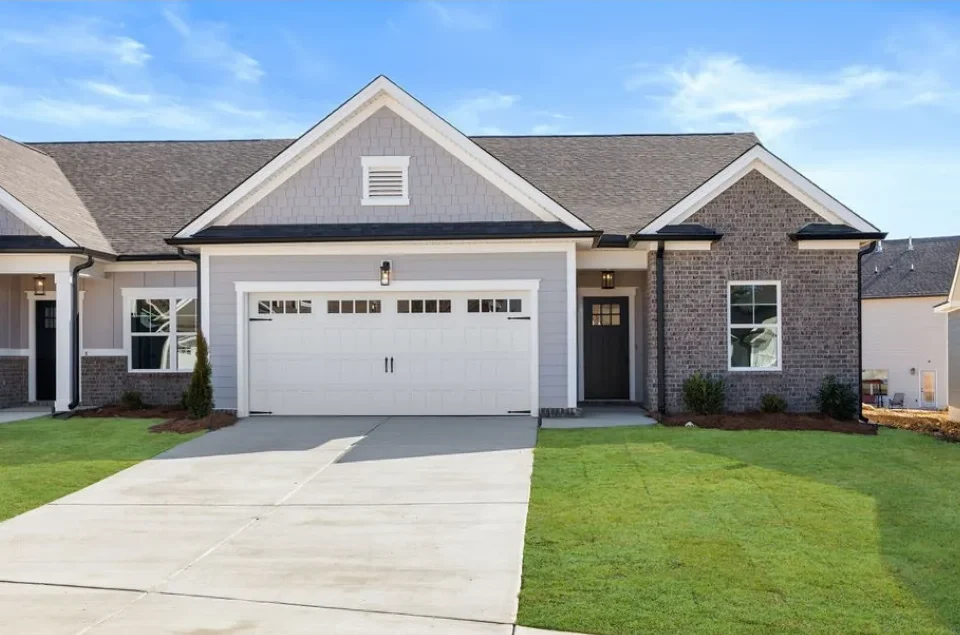 New Home Chattanooga TN. Modern single-story brick home with a two-car garage, fresh lawn, built by Pratt Home Builders under clear blue skies.