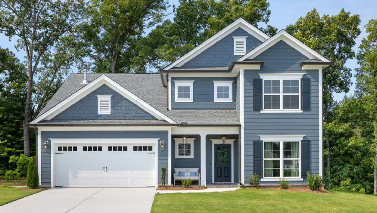 Waterford-floor-plan-front-exterior-home-for-sale Two-story gray house with white trim, double garage, and front porch. Built by Pratt Home Builders in Chattanooga TN, surrounded by green trees.
