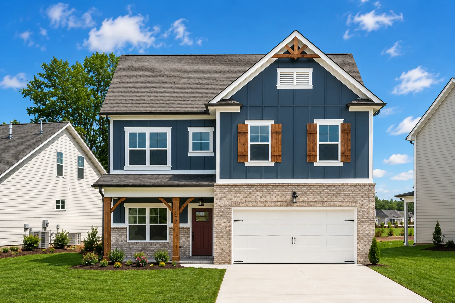 Quail-run-floor-plan-front-exterior-homes-for-sale Two-story house with dark blue siding and brick facade, wooden shutters, and a white garage by Pratt Home Builders in Chattanooga, TN.