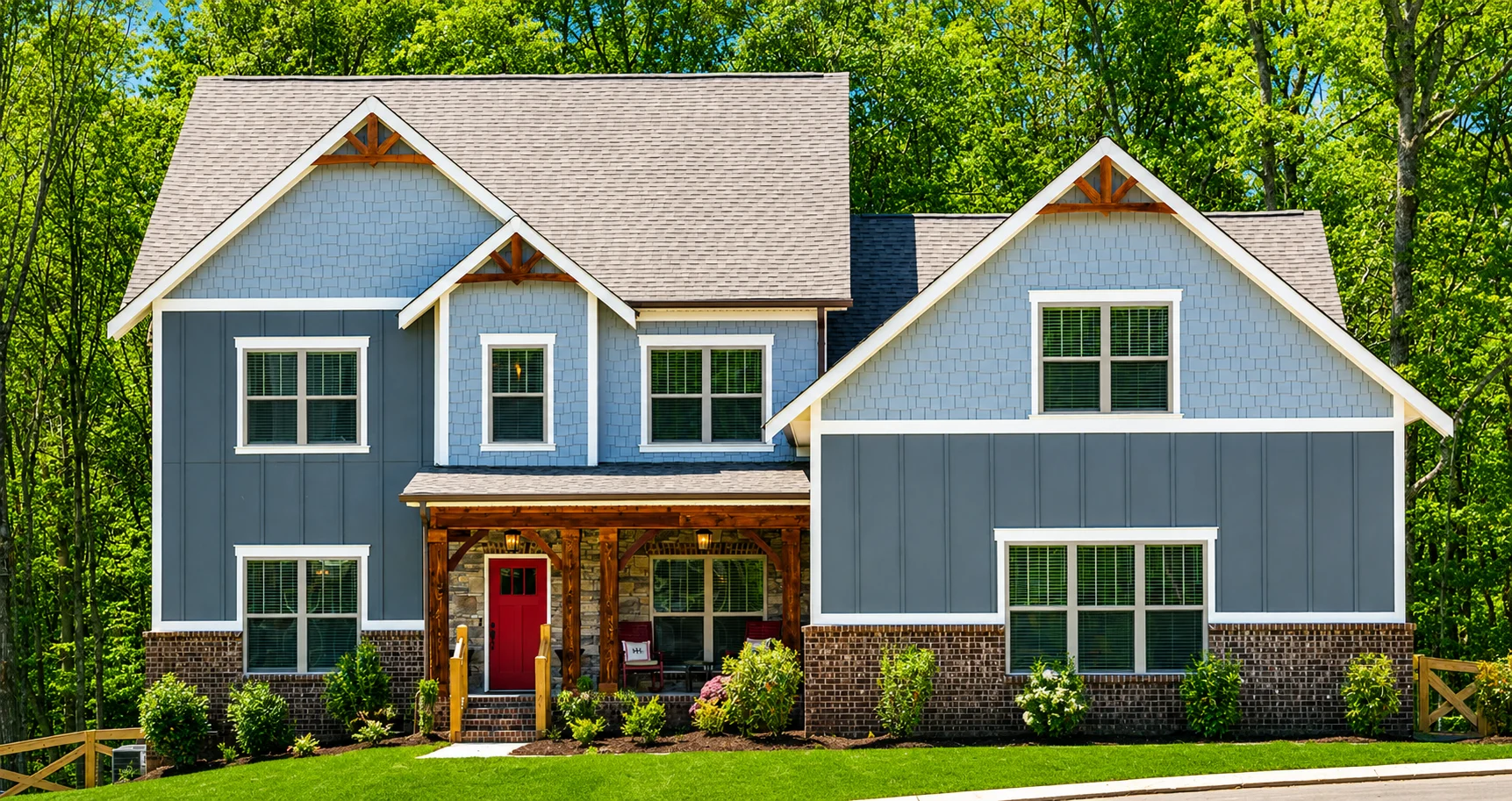 Two-story blue house with a red door, stone and brick accents, surrounded by trees, built by Pratt Home Builders in Chattanooga TN.