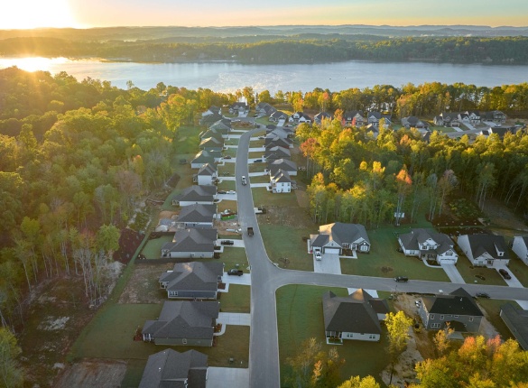 Aerial view of a serene Soddy Daisy community by a lake, surrounded by lush trees, built by Pratt Home Builders in Chattanooga TN at sunrise.