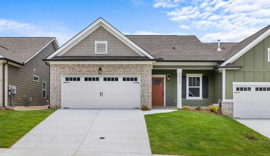 New Home Chattanooga TN. Modern single-story home with brick and green facade, featuring double garage doors. Built by Pratt Home Builders.