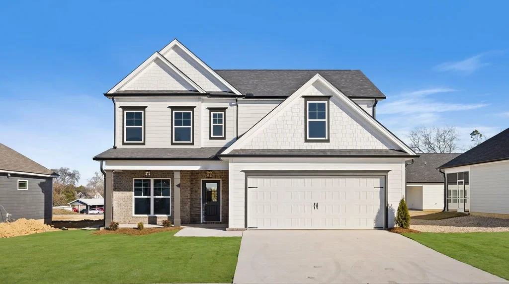 A_Ext Front Two-story modern house with a large garage and green lawn, built by Pratt Home Builders in Chattanooga, TN, under a clear blue sky.
