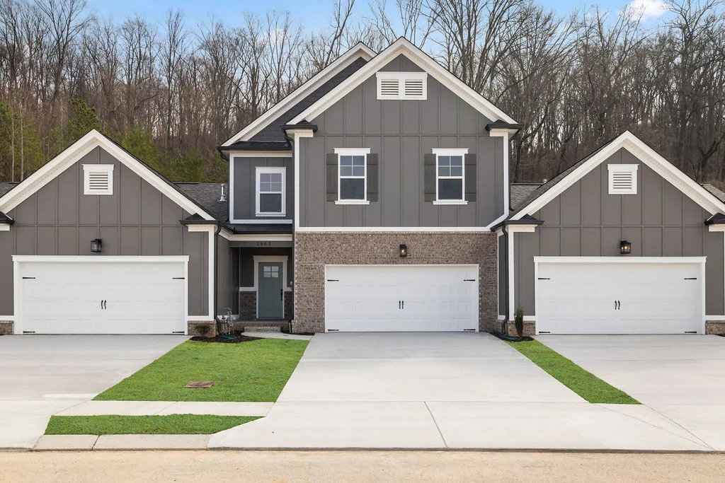 New Home Chattanooga TN. Modern gray townhouse with three white garage doors, built by Pratt Home Builders surrounded by trees.