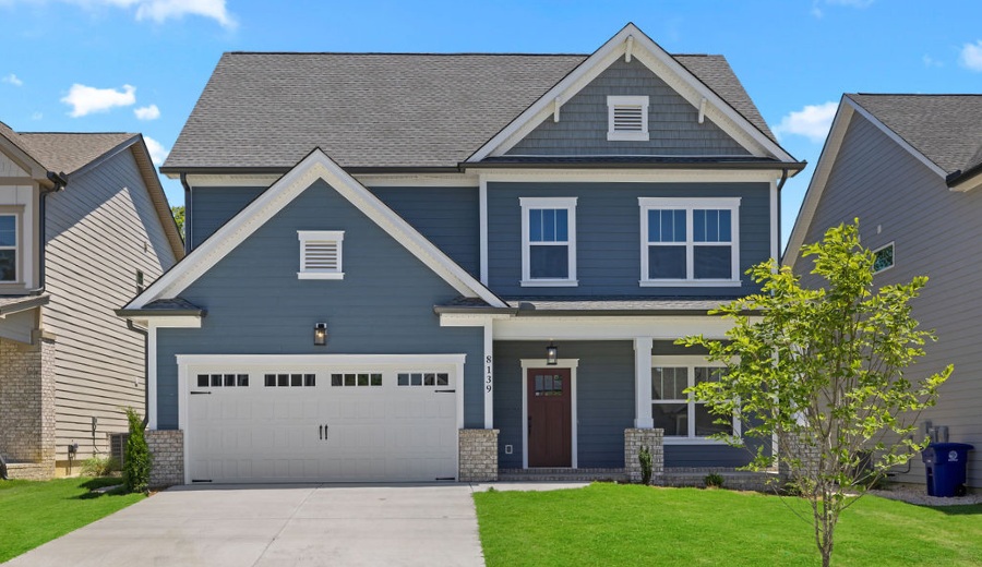 Two-story gray house with white trim, gabled roof, and a two-car garage. Built by Pratt Home Builders in Chattanooga, TN. Lush green lawn.