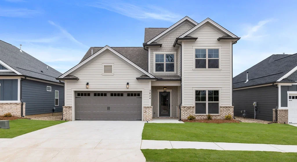 Modern two-story home with brick accents, gray garage door, and manicured lawn, built by Pratt Home Builders in Chattanooga TN.