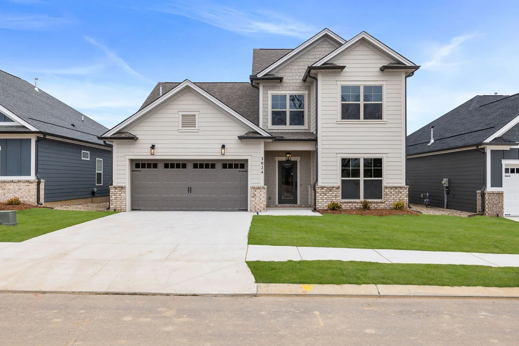 Modern two-story home with brick accents, gray garage door, and manicured lawn, built by Pratt Home Builders in Chattanooga TN.
