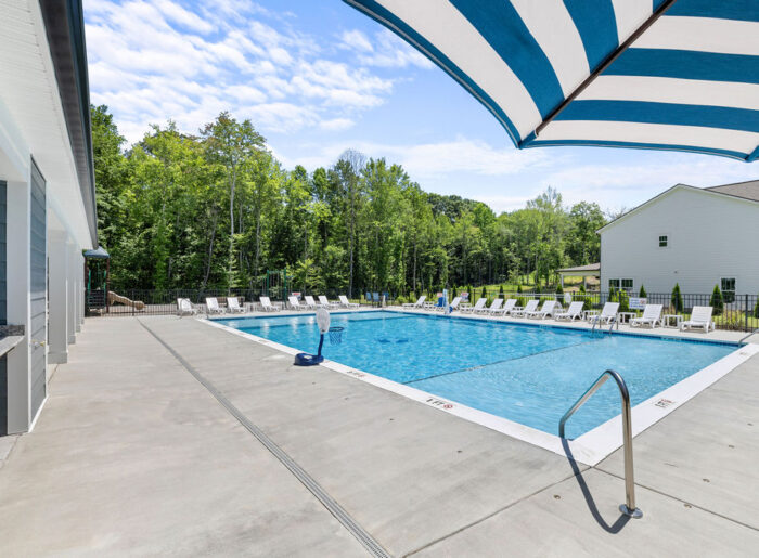New Home Chattanooga TN. Outdoor pool surrounded by white chairs and nature, under blue sky. On property of Pratt Home Builders.
