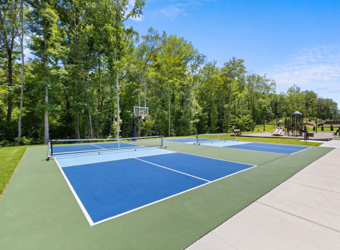 New Homes Chattanooga TN. Pickleball and basketball courts with forest backdrop near playground, developed by Pratt Home Builders.