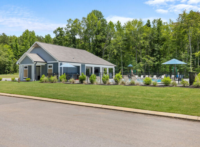 Community clubhouse and pool with umbrellas, surrounded by greenery, built by Pratt Home Builders in Chattanooga TN.
