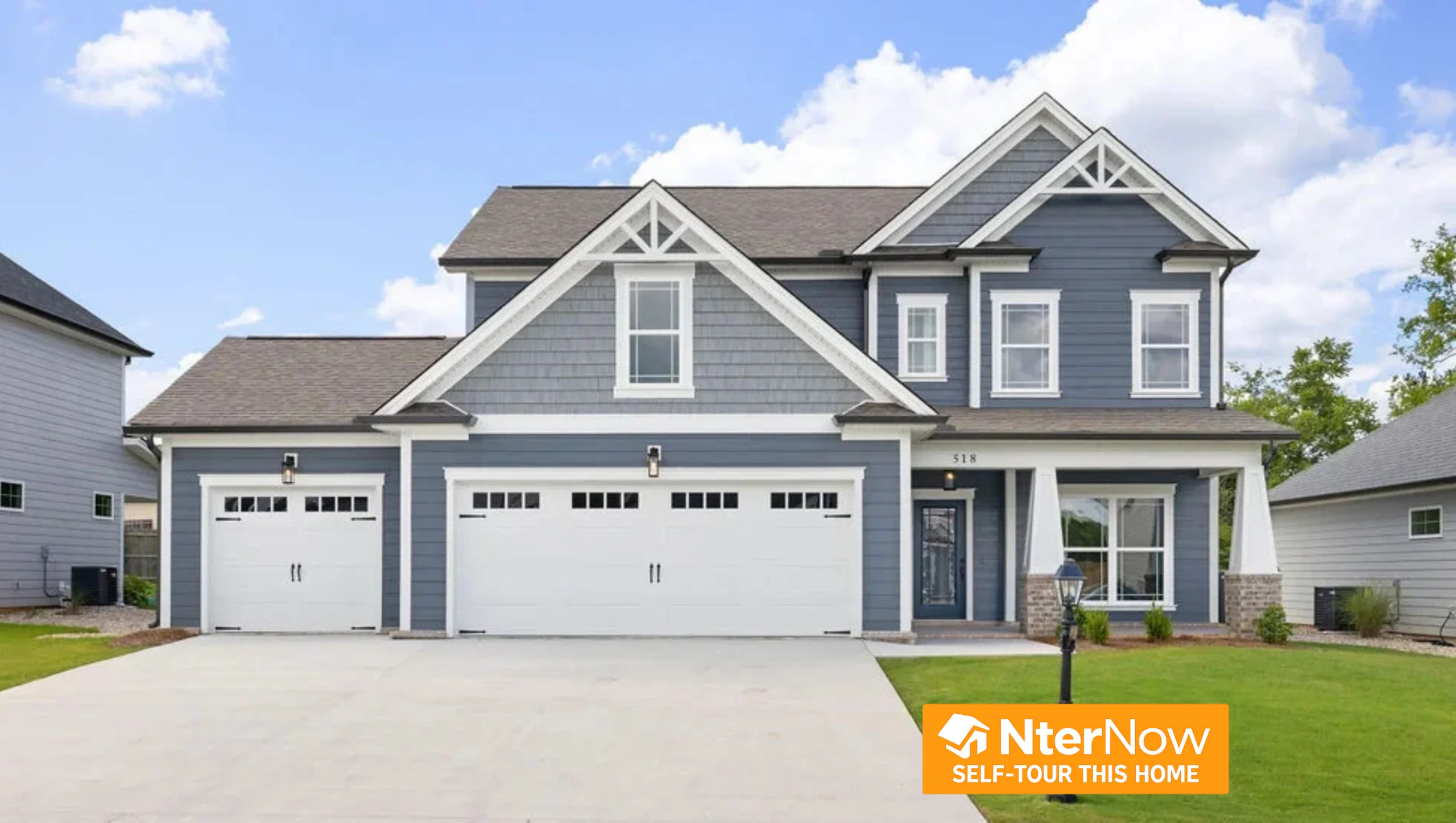 Two-story blue house with white trim and three-car garage, built by Pratt Home Builders in Chattanooga TN; NterNow self-tour sign in corner.