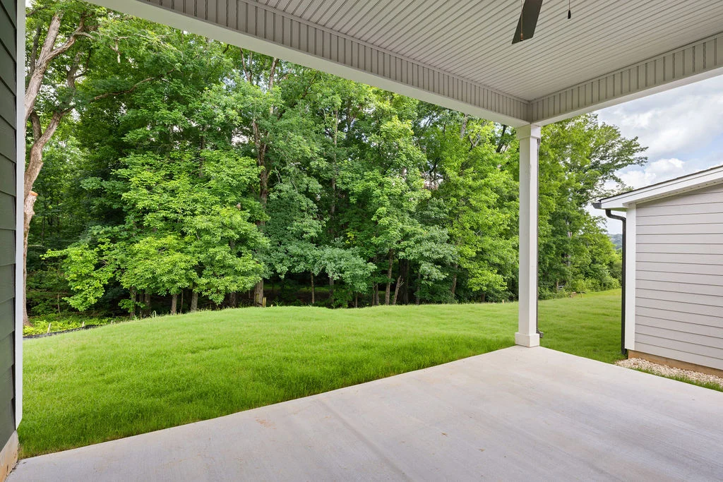 Concrete patio with lush green lawn and forest view, featuring construction by Pratt Home Builders in Chattanooga TN.