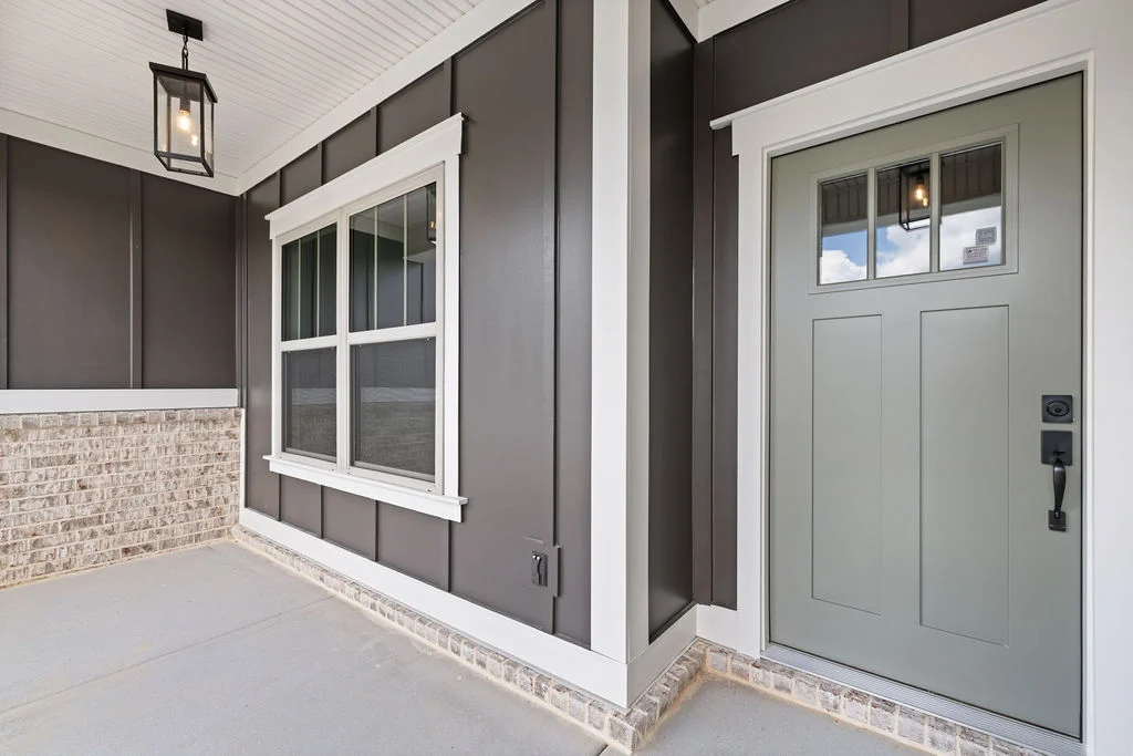 Stylish porch by Pratt Home Builders in Chattanooga TN, featuring gray door, brick accent, and modern pendant light.