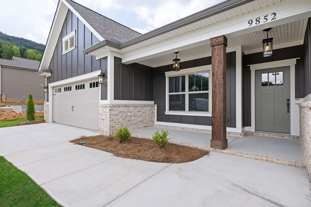 Modern farmhouse exterior by Pratt Home Builders in Chattanooga TN, featuring grey siding, white trim, and wooden columns with a spacious driveway.