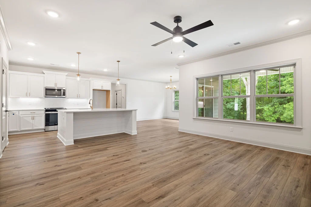 Open concept kitchen with island, modern appliances, large window, and wood flooring by Pratt Home Builders in Chattanooga TN.