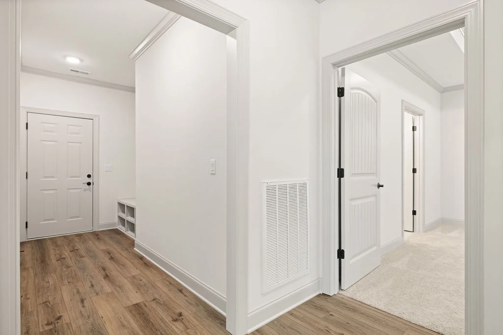 Bright hallway with wood flooring, white walls, and multiple doors; built by Pratt Home Builders in Chattanooga TN.