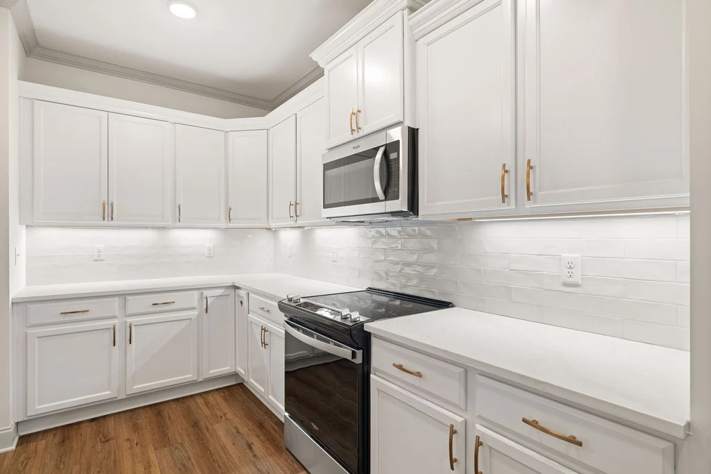 Modern kitchen with white cabinets, stainless steel appliances, and wood floors by Pratt Home Builders in Chattanooga TN.