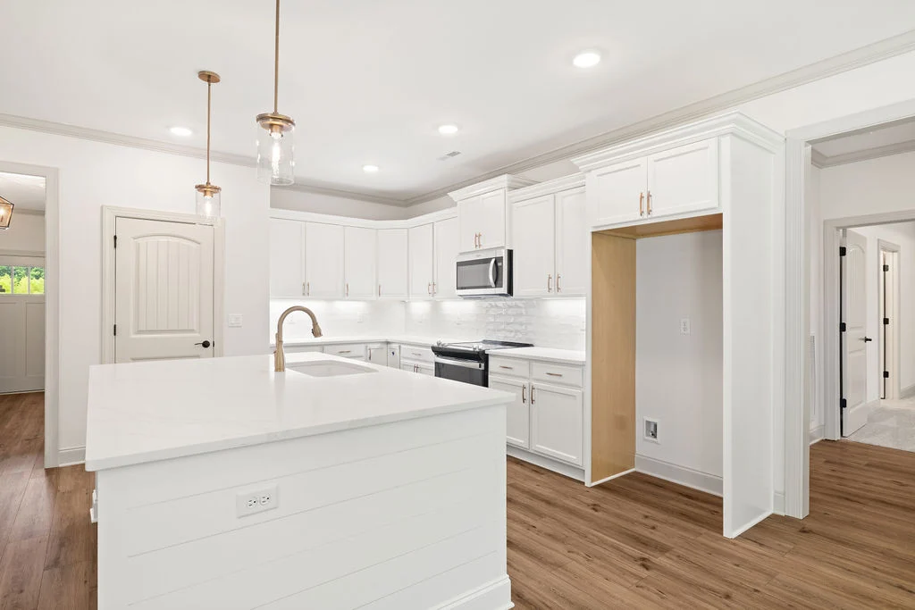 Modern kitchen interior with white cabinets, stainless steel appliances, and a spacious island. Designed by Pratt Home Builders in Chattanooga TN.