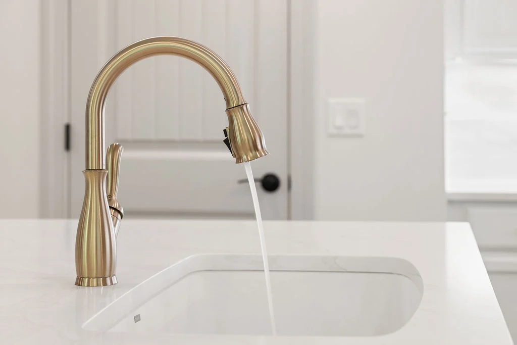 Bronze kitchen faucet runs water into a white marble sink, designed by Pratt Home Builders in Chattanooga TN.