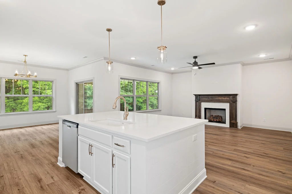 Spacious kitchen and living area by Pratt Home Builders in Chattanooga, TN, featuring a large island, wood floors, and a fireplace.