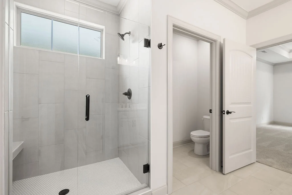 Modern bathroom with glass shower, adjacent toilet, and soft lighting, designed by Pratt Home Builders in Chattanooga TN.
