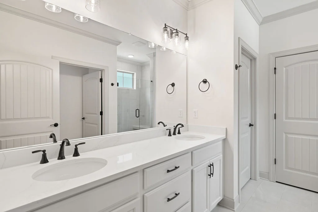 Elegant bathroom with double sink vanity, industrial light fixtures, and modern cabinets by Pratt Home Builders in Chattanooga TN.