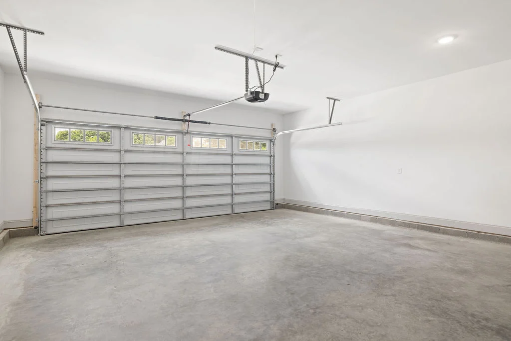 Spacious garage interior by Pratt Home Builders in Chattanooga, TN, featuring a double-door, concrete floor, and bright white walls.