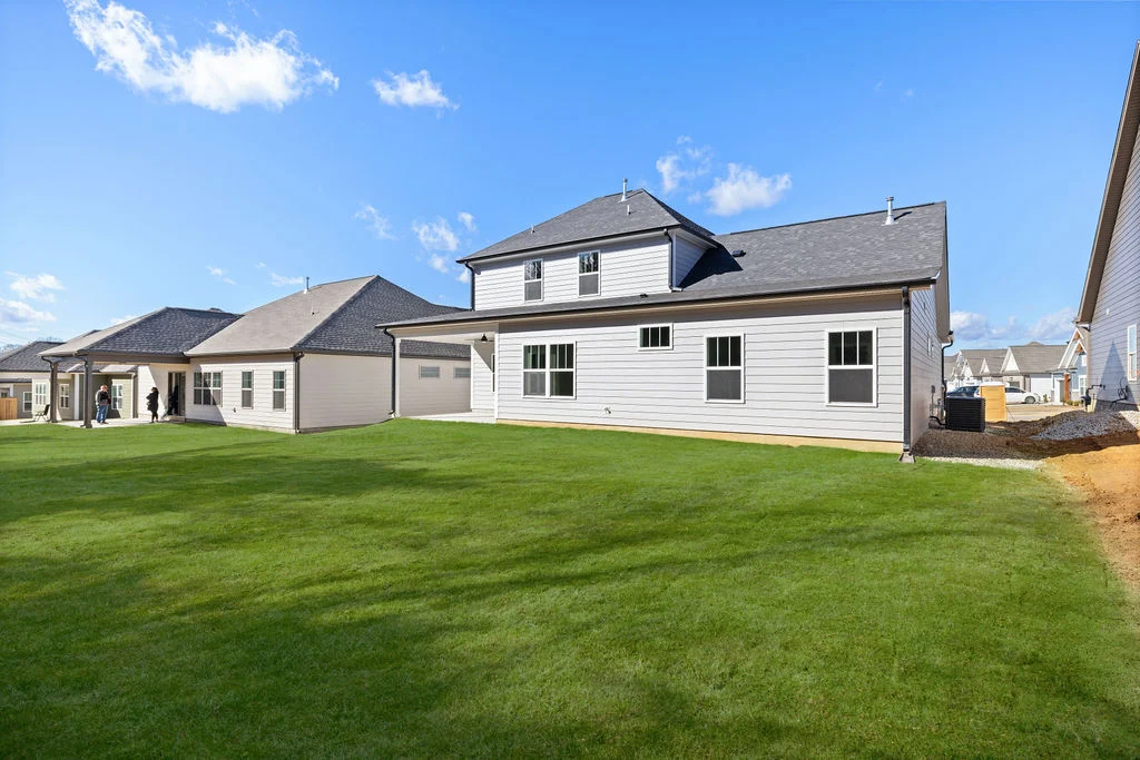 Spacious backyard of a modern two-story home by Pratt Home Builders in Chattanooga, TN, under clear blue skies.
