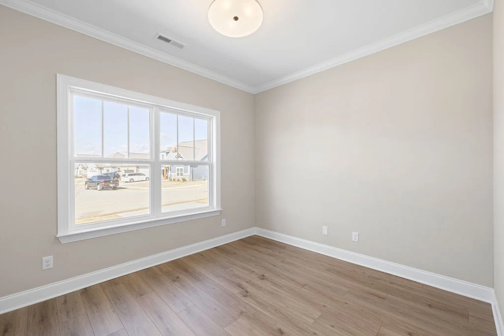 Bright office or bedroom space with hardwood floors, large window, and neutral walls by Pratt Home Builders in Chattanooga TN.