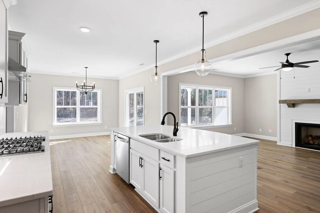 Open-concept kitchen and living area by Pratt Home Builders in Chattanooga TN, featuring white cabinetry, center island, and modern lighting.