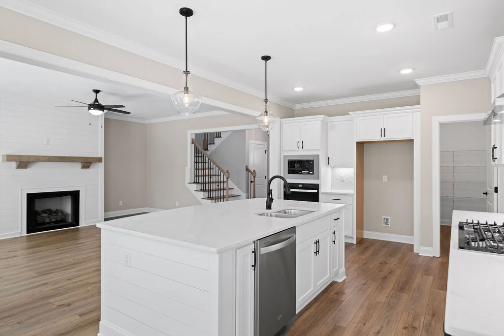 Designer kitchen with white cabinets, island, stainless steel appliances, open to living room. Designed by Pratt Home Builders in Chattanooga TN.