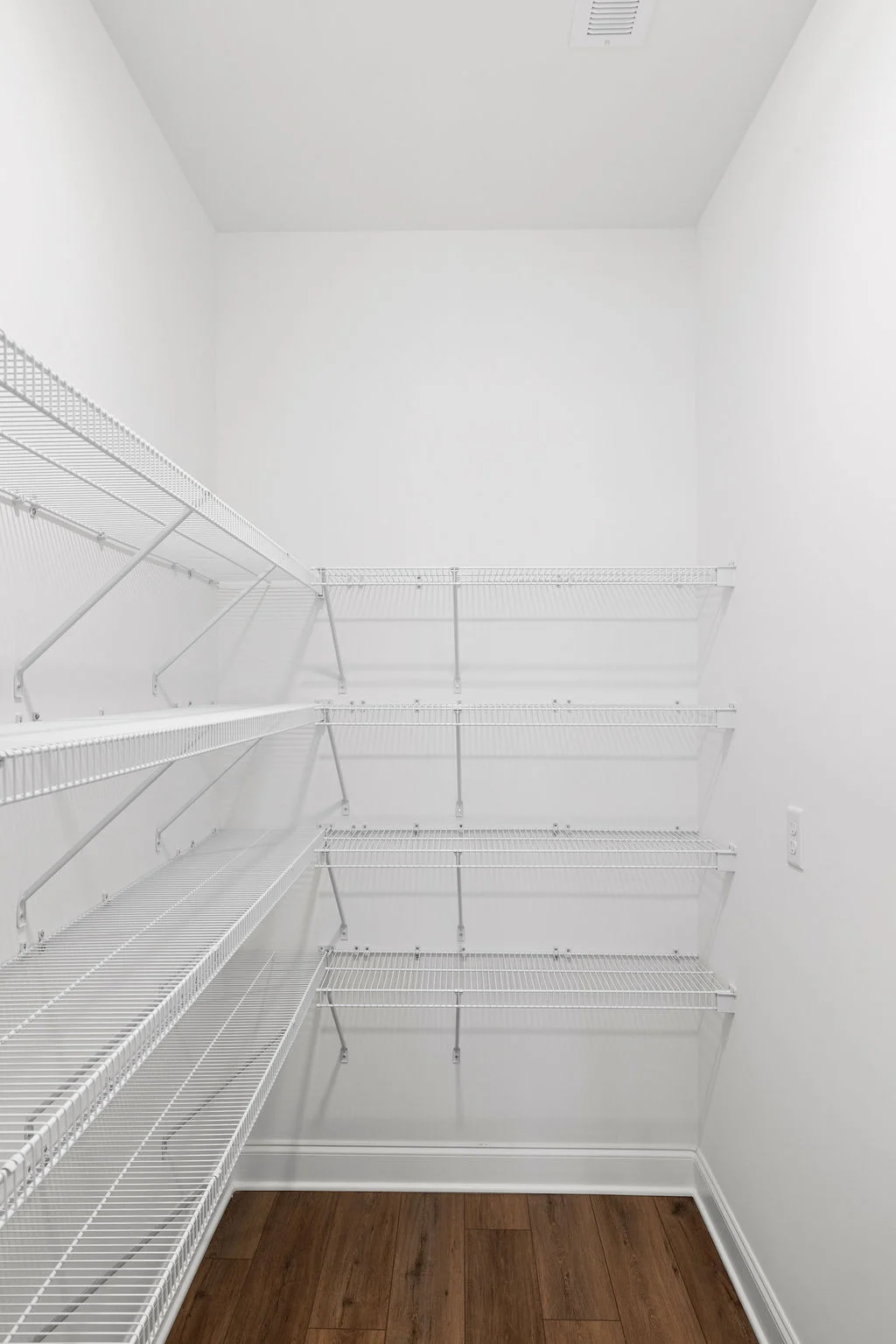 Walk in pantry with built-in shelves and wood flooring, designed by Pratt Home Builders in Chattanooga TN.