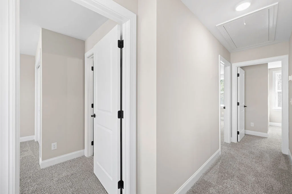 Bright hallway with beige walls, white doors, and carpet flooring, typical of Pratt Home Builders in Chattanooga TN.