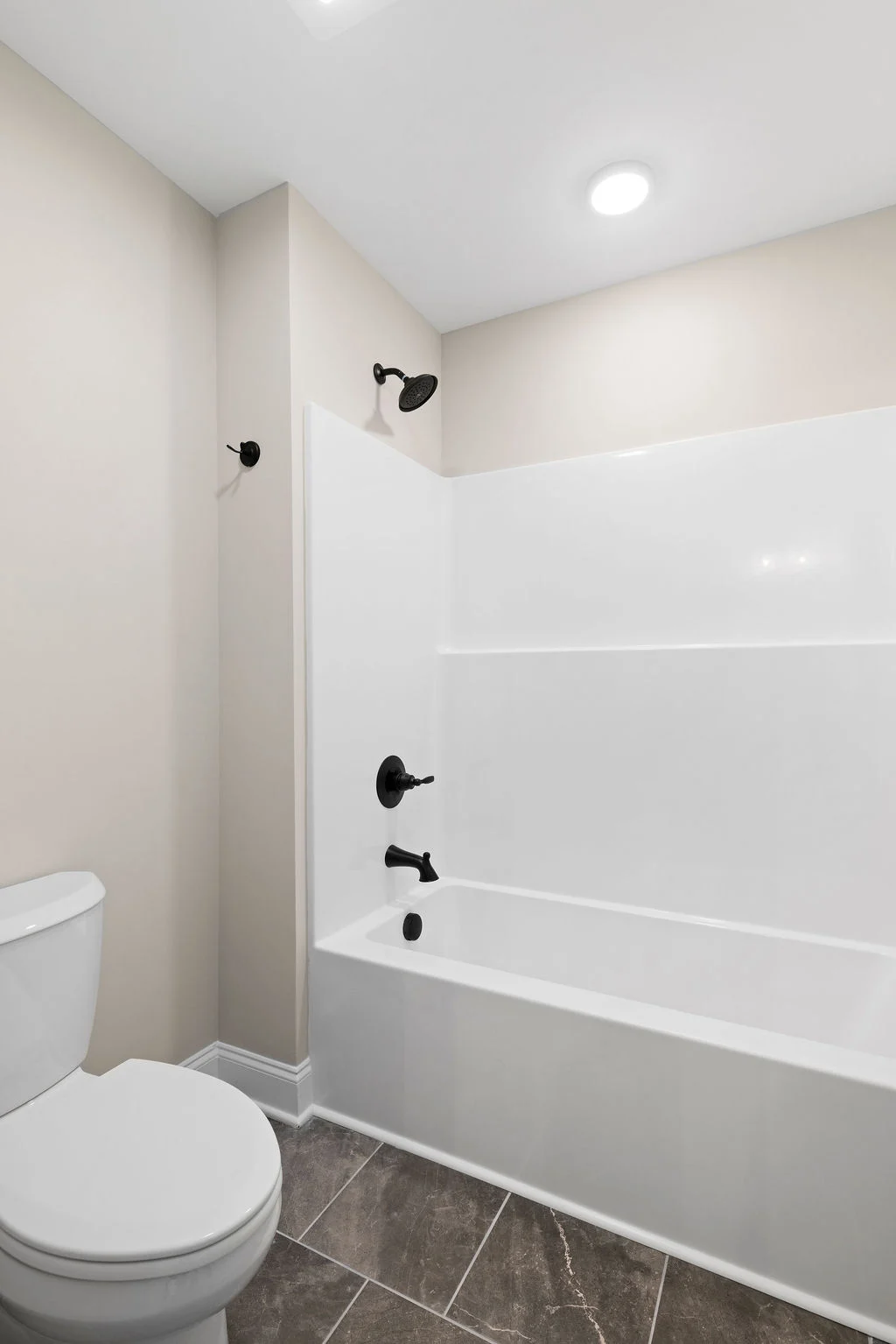 Modern bathroom with white fixtures, brown tiled floor, and black hardware by Pratt Home Builders in Chattanooga TN.