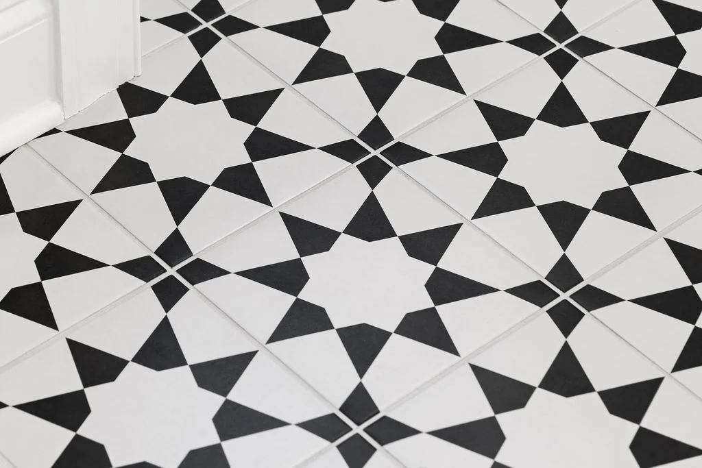 Black and white geometric patterned floor tiles arranged in a repeating star design
