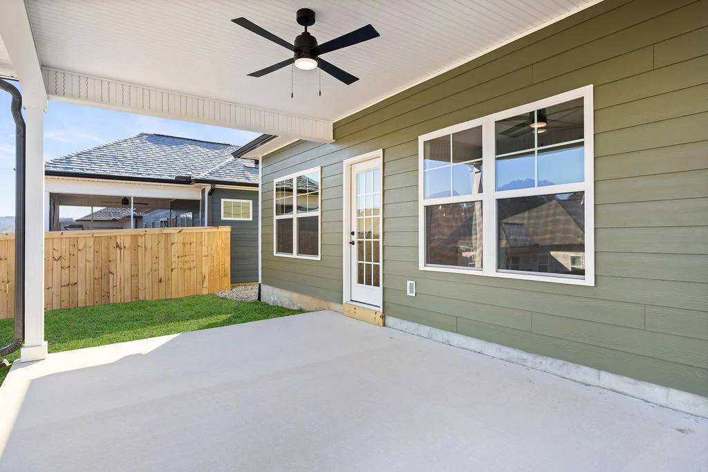 Covered patio with ceiling fan, green siding, and window. Wooden fence encloses backyard. Built by Pratt Home Builders in Chattanooga, TN.