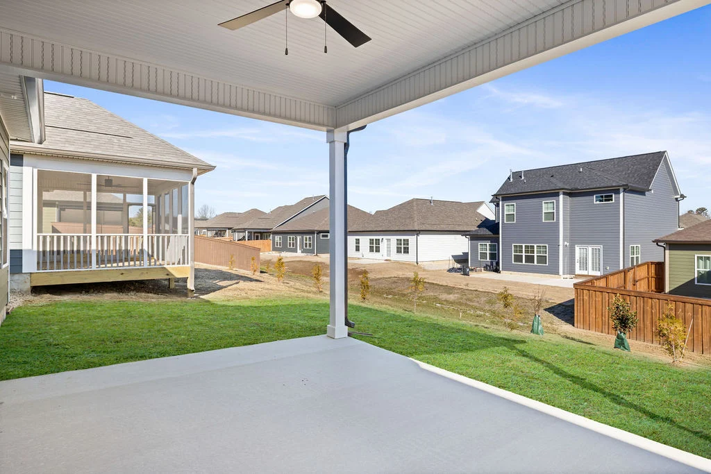 Covered patio with ceiling fan overlooking a residential neighborhood. Homes by Pratt Home Builders in Chattanooga TN, featuring fenced yards.