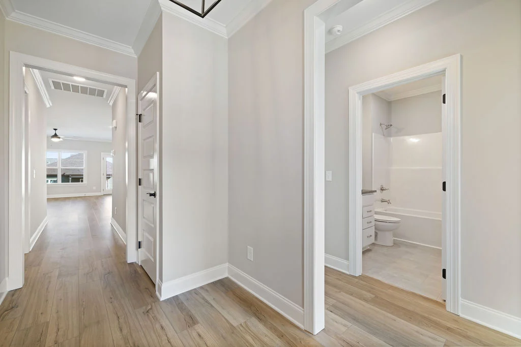 Bright hallway with wood flooring, leading to a living room and bathroom; design by Pratt Home Builders in Chattanooga TN.