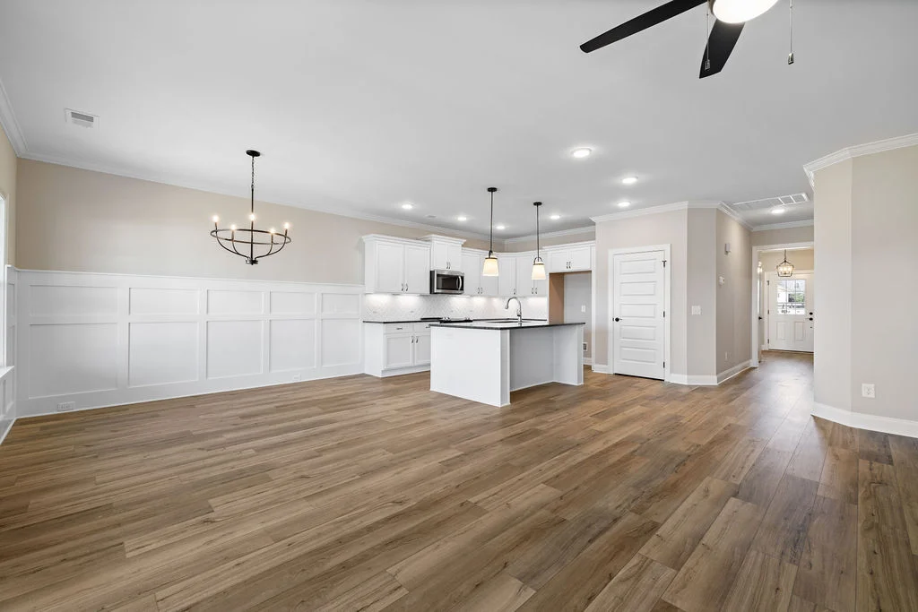 Spacious modern kitchen and dining area by Pratt Home Builders in Chattanooga TN, featuring wood flooring and elegant lighting fixtures.