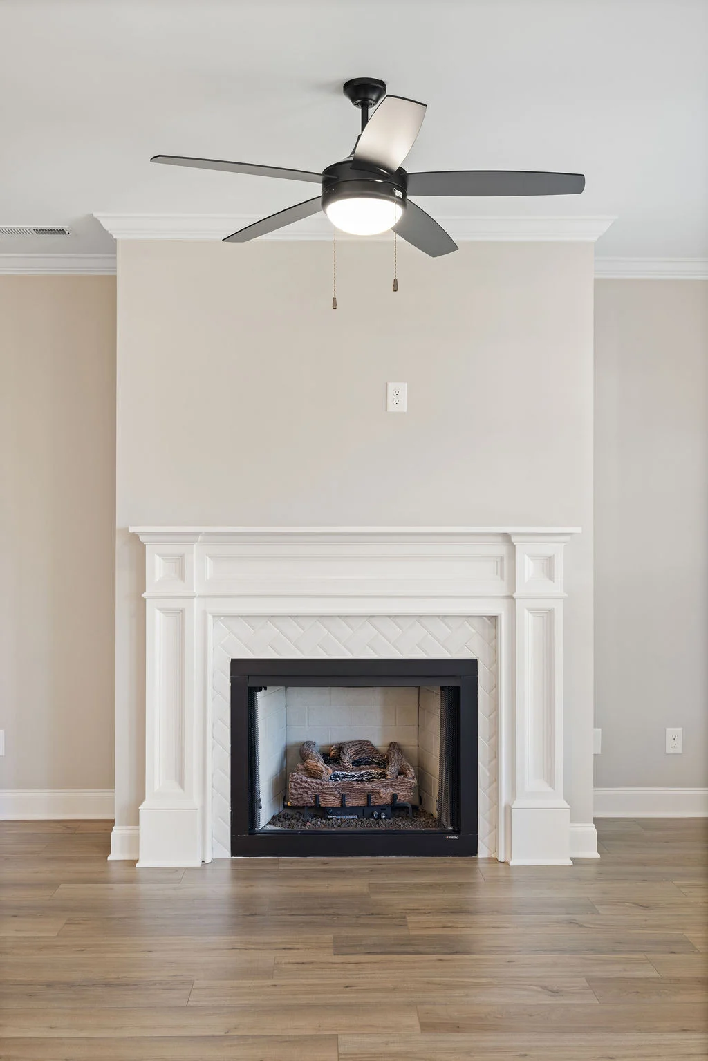 Elegant room with white mantel fireplace, sleek ceiling fan, and wooden flooring by Pratt Home Builders in Chattanooga TN.
