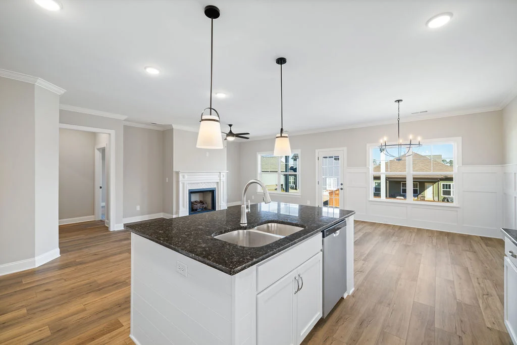 Modern kitchen and living area with island, pendant lighting, and fireplace, showcasing Pratt Home Builders in Chattanooga TN.