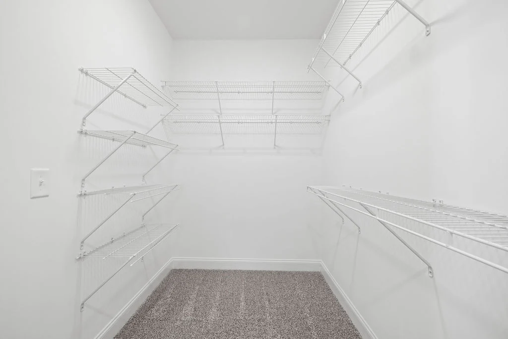 Spacious white walk-in closet with wire shelves on three walls. Designed by Pratt Home Builders in Chattanooga TN.