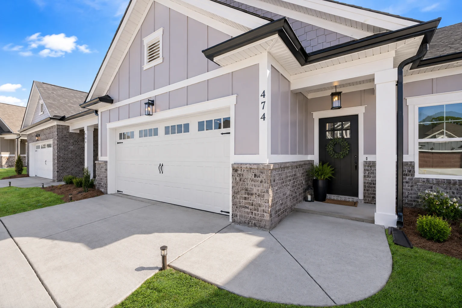 Modern home with a two-car garage, gray siding, and brick accents by Pratt Home Builders in Chattanooga, TN. Neatly landscaped front yard.